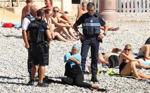 Femeie purtând burkini, forţată de poliţişti să-şi îndepărteze veşmântul