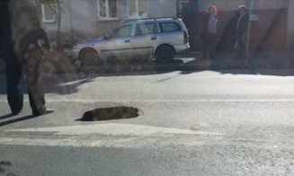 Crater în asfalt pe o stradă din centrul Clujului. Oamenii au ieşit cu găleata
