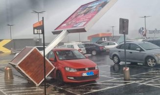 Panou publicitar CĂZUT peste mașina unui clujean în parcarea unui mall